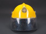 yellow fireman ' s helmet with clear visor and badge on it