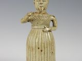 une vieille figurine en céramique représentant une femme en robe et avec un chapeau