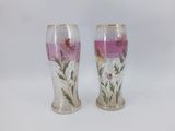 two vases with flowers painted on them sitting on a table