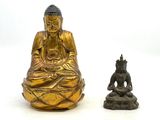 deux statues de bouddhas assis l'une à côté de l'autre sur une surface blanche