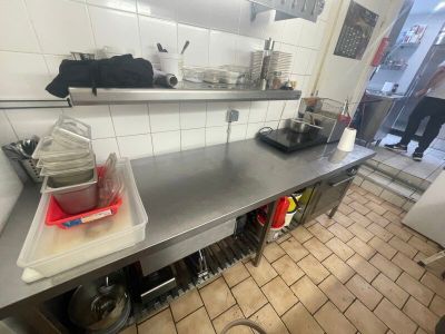 plan de travail en acier inoxydable dans une cuisine commerciale avec des casseroles et des poêles dessus