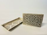 two silver trays with intricate designs on them on a white surface