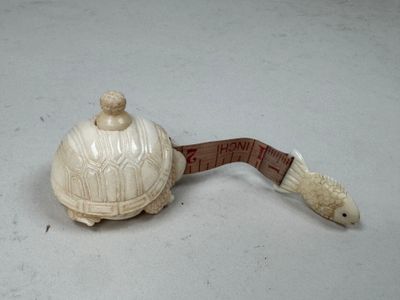 une petite tortue assise sur un mètre ruban