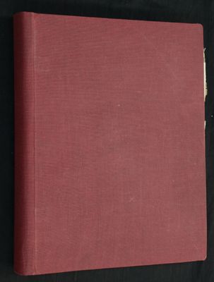 un livre rouge posé sur une table recouverte d'un tissu noir