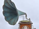 un vieux gramophone dans un coffret en bois posé sur une surface blanche