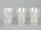 trois verres à pied en verre transparent posés les uns à côté des autres sur une table