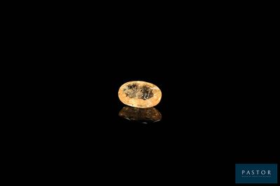 un diamant jaune sur une surface noire, avec un reflet