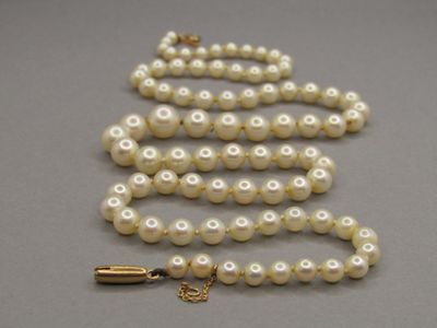 collier de perles avec un fermoir en or sur un fond gris
