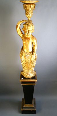a gold statue of a boy holding a bowl on top of his head