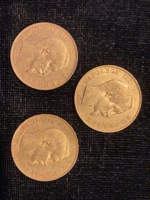 trois pièces d'or posées sur un tissu noir