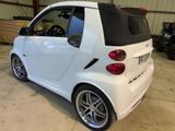 a small white car with a black top parked in a garage
