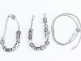 three silver bracelets and a necklace on a white background