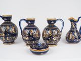 trois vases bleus et dorés et un bol posés sur une surface blanche