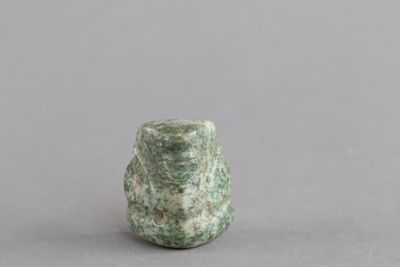 une image représentant un petit objet en pierre verte posé sur une surface grise