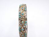 a close up of a gold and turquoise bracelet on a white background