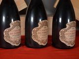 three bottles of wine are lined up on a red cloth