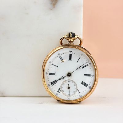 une montre de poche en or posée sur un bloc de marbre