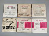 four beatles records are on a table with pink covers