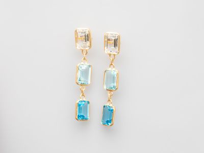 une paire de boucles d'oreilles en topaze bleue et en topaze blanche sur fond blanc