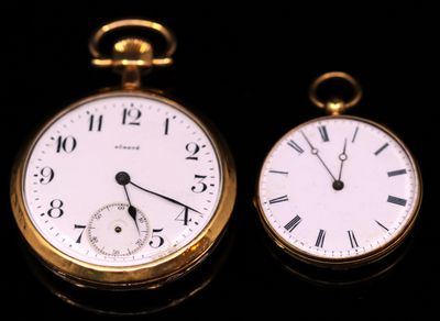 two gold pocket watches sitting side by side on a black surface
