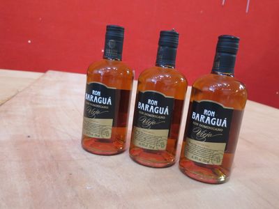 trois bouteilles de rhum posées sur une table devant un mur rouge