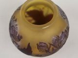 a yellow vase with purple flowers on it on a white surface