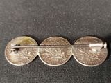 a close up of a metal pin with three coins on it