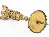 a gold candle holder with a green stick sticking out of it