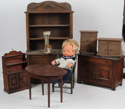 une poupée assise à une table devant un ensemble de meubles