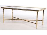 une table basse en laiton avec un plateau en verre et des pieds en métal