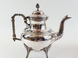 an antique silver teapot with a handle on a stand