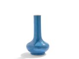 un vase bleu posé sur une surface blanche