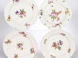quatre assiettes ornées de motifs floraux, posées sur une surface blanche