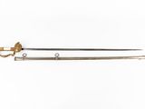 a close up of a sword on a white surface with a gold handle
