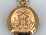 an image of a gold pocket watch with a monogram on the front