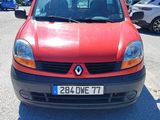 une voiture rouge garée sur un parking, avec d'autres voitures en arrière-plan