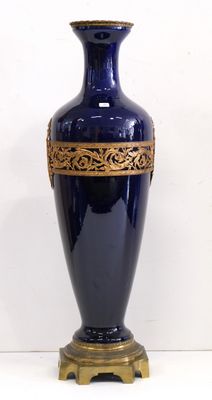 un vase bleu orné de motifs dorés sur un fond blanc