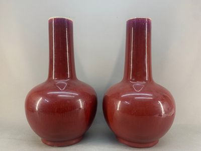 pair of red vases sitting on top of a table next to each other