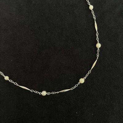 a necklace with pearls and gold beads on a black background