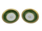 two green and white plates with gold rims on a white surface