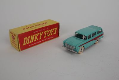 une petite voiture Dinky Toy avec une boîte de jouets Dinky Toys posée sur une surface blanche