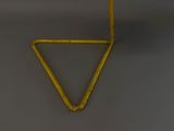 an old yellow triangle shaped object hanging on a gray wall