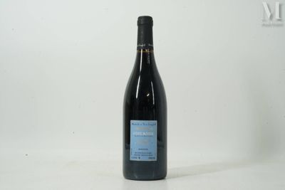 the bottle of wine is sitting on the table next to the wall