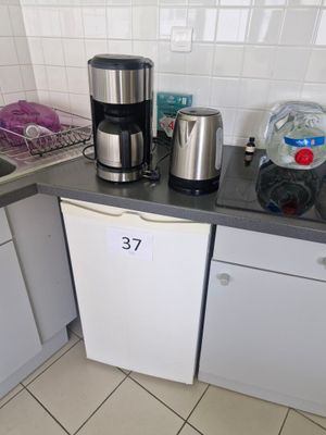 une petite cuisine avec une cafetière posée sur le plan de travail