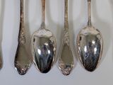 several spoons and forks are lined up against a white wall