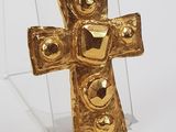a gold cross on a clear stand on a white surface