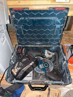 une mallette à outils ouverte, contenant des outils, posée par terre