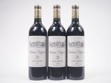 trois bouteilles de vin rouge posées l'une à côté de l'autre sur une surface blanche