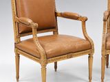 pair of carved and upholstered armchairs with leather upholstered seats