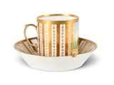 une tasse et une soucoupe posées sur une assiette à bord doré